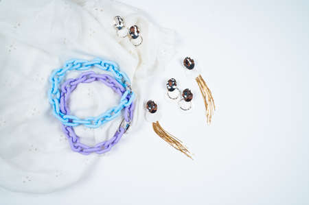 Women's jewelry. Stylish women's neck jewelry and earrings on white crumpled fabric background. High...
