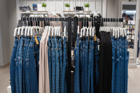 Row of jeans hung on plastic hangers in store. Many jeans are hanging on counter. High quality photoの写真素材