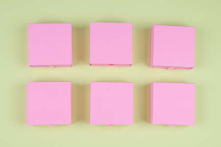 Lot of square pink carton boxes on green background. High quality photo