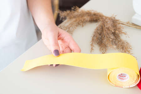 The beautician holds tapes in her hands on light background, cropped view. Anti-aging proceduresの写真素材