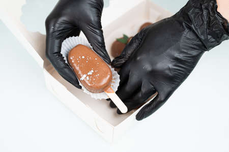 Pastry chef in protective packing dessert in gift box. Chocolate cake pops in the form of ice cream on a stick.の写真素材