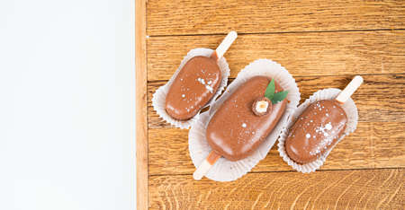 Chocolate cake pops in the form of ice cream on a stick. On a wooden stand, top view. Concept food,...