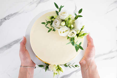 Birthday cake with flowers in female hands, top viewの写真素材