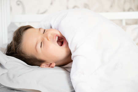 Cute little boy wake up in his comfortable bed in the morning and yawns. good morning. high quality...