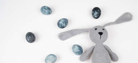 Toy rabbit hunter with blue Easter eggs isolated on white. Happy Easter concept