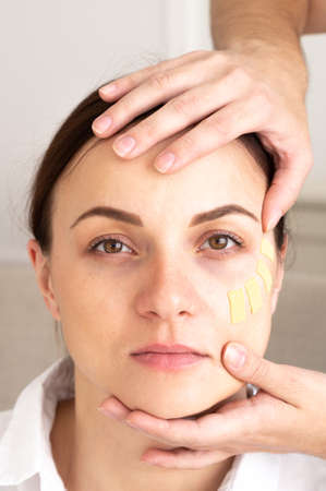 Beautician hands and close-up portrait of young woman with lifting treatment on face. face and body...