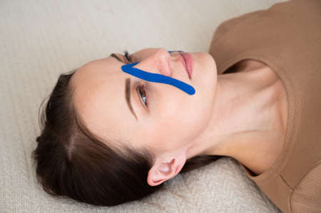 Attractive woman taking skin care, blue kinesiotape of the face. Lifting skin concept.の写真素材