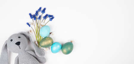 Easter card with bunny toy, bouquet of flowers and painted easter eggs on white background with copy space.の写真素材