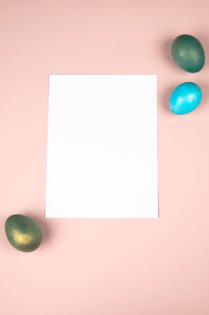 Easter composition with white blank paper and eggs on pastel pink background.の写真素材