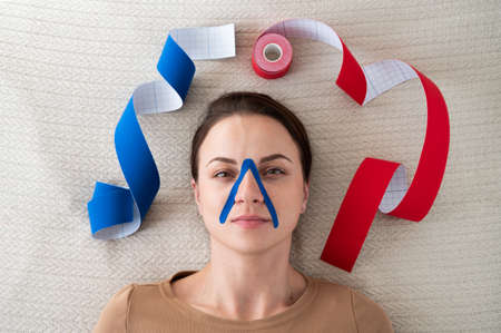 Portrait of a woman with a kinesiotape of the face. Aesthetic taping concept.