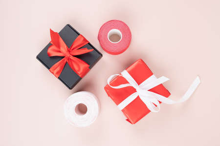 Top view of kinesio tape rolls and gift boxes on pink surface. Anti-aging treatment against...
