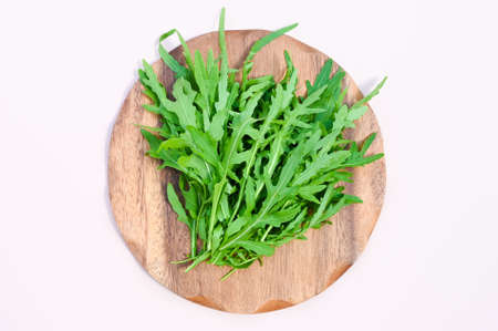 Fresh green arugula on wooden plate top view. Healthy food or vegetarian concept. Copy space