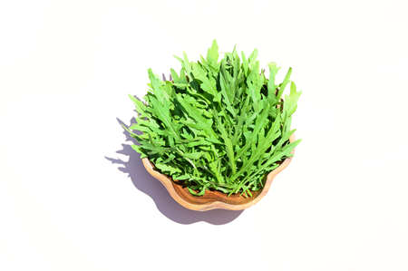 Fresh green arugula leaves on wooden bowl, rucola salad in the rays of sunlight, top view with place for textの写真素材
