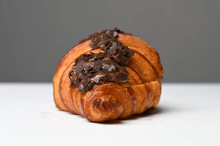 Croissant with chocolate chip topping on white table. side view.の写真素材