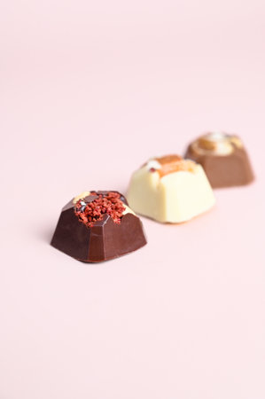 Artisan handcrafted chocolate bonbons with fruit and nuts filling. Mixed chocolate candies on pink...