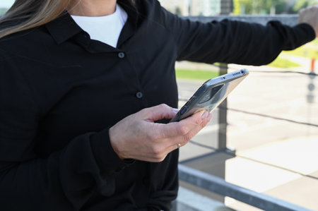 Close-up of lady using mobile phone for important communication. Busy woman in black shirt using...