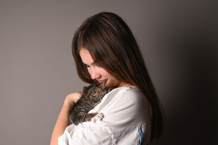 Young girl holding a baby cat on gray background. Female hugging her cute kitty. Adorable domestic pet concept.の写真素材