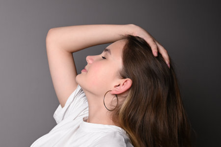 Portrait of a young beautiful teen model in white shirt on gray background. Teen face in profile.