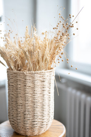 Dry wild flowers over white background. A wicker vase with dried plant. Boho style. Vertical viewの写真素材