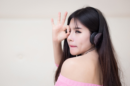 young woman listening music in headphones on her bedの写真素材
