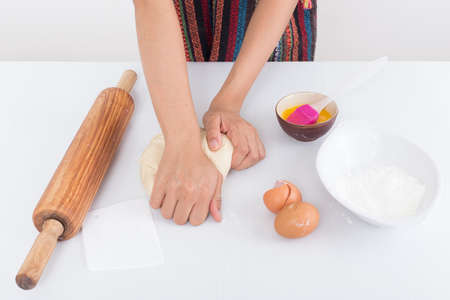 Female hands baking dough on white background