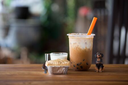 Ice bubble milk tea in takeaway glass on wooden plate - blurry background