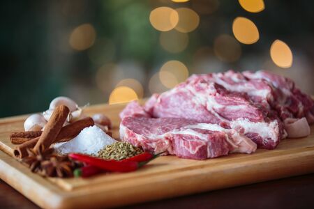 Close up raw pork with herbs on cutting board - bokeh backgroundの写真素材