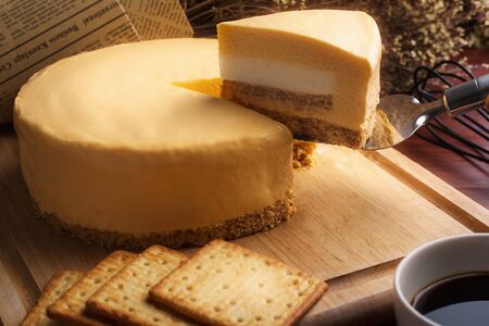 Emmental cheese cake with Mascarpone cheese cake inside with coffee and biscuit on wooden table....