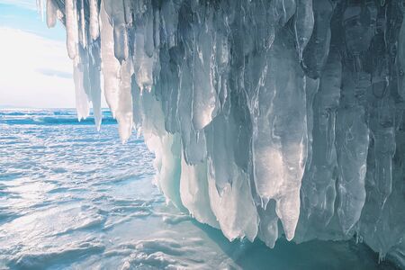 Blocks of ice at the entrance to the ice grotto. Turquoise ice and snow around. Deserted. Frozen small sea.の写真素材