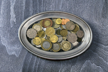 heap of different coins on a silver platterの写真素材