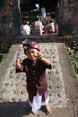 BALI, INDONESIA - SEPTEMBER 2,2012: barefoot boy stretches his hands on the Balinese ceremonyのeditorial素材