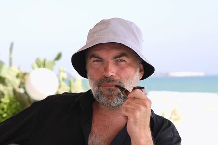 Bearded man smoking a pipe on the sea shoreの写真素材
