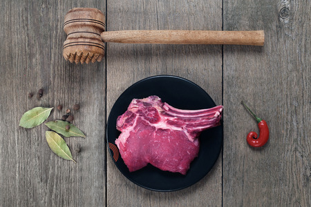 piece of beef with bone, spices and a hammer for meatの写真素材