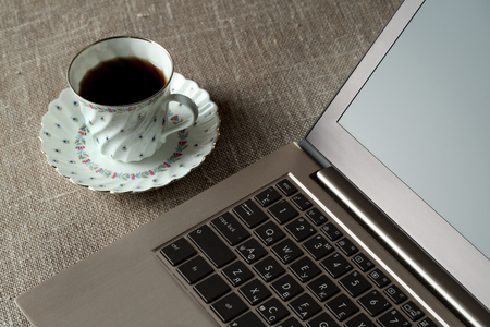 A cup of tea and a laptop on the tableの写真素材