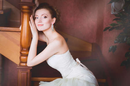 Beautiful bride sitting on wooden stairsの写真素材