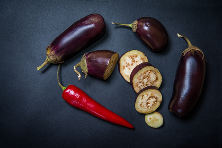 eggplant with chilli peppers on a dark surface, sliced ??eggplant and chili pepperの写真素材