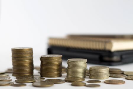 stack of coins and calculator with note book on the table. copy space. finance. payment of billsの写真素材