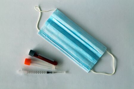 Disposable surgical face mask. Medical protective mask, syringe and test tube with blood isolated on...