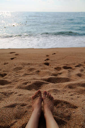feet on the beach with yellow sand and blue sea. summer and rest day. vertical