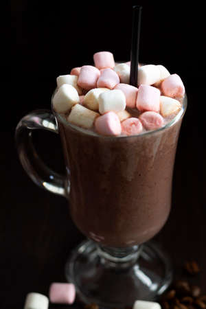 cup of coffee with marshmallows. glass of cappuccino on a dark table. hot chocolate on a wooden background. hot drinks winter and autumn. vertical. copy spaceの写真素材
