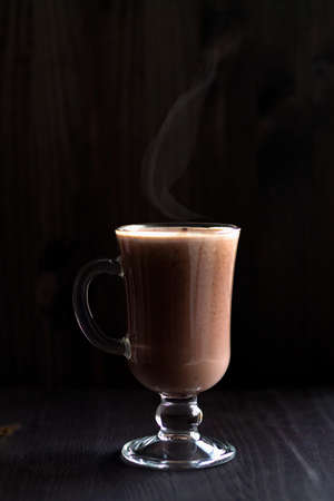 cup of hot chocolate. glass of cappuccino on a dark table. drinks on a wooden background. hot drinks winter and autumn. vertical. copy spaceの写真素材
