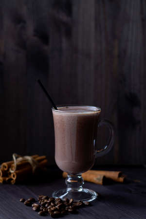 cup of cappuccino.hot drinks winter and autumn. glass of hot chocolate with whipped cream, coffee beans and cinnamon sticks on a dark background. hot drinks on a wooden background. vertical.copy spaceの写真素材