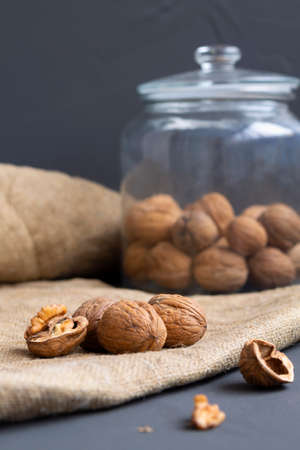 walnuts. unpeeled and peeled walnuts in shells on a black table and in a glass jar. brown nuts with...