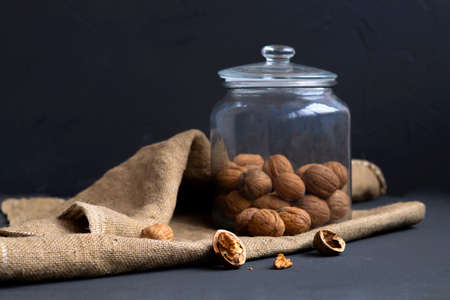 dried walnut and fruit. walnuts. unpeeled and peeled walnuts in shells on a black table and in a...