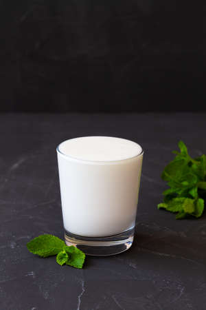 Lassi drink with fresh green mint. cold dairy. Indian cuisine. copy space. ayran, milk with probiotics on the dark table. healthy, fermented products concept. verticalの写真素材