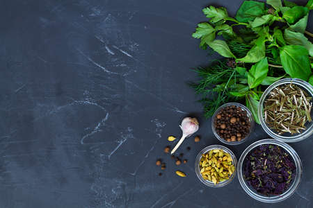 herbs and spices.fresh and dry spices for cooking. food ingredients on the black table. flat lay background with green herbs, spices and garlic with copy space. top view.の写真素材
