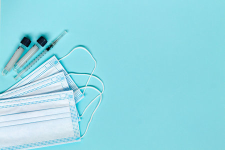 tablets and pills, medical face masks and injection, ampoules with medication on blue background with copy space. concept covid-19 top view. vaccinationの写真素材