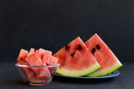 slice of watermelon on plate.red watermelon in a glass bowl on the black background. fresh watermelon on the gray plate on the table with copy spaceの写真素材