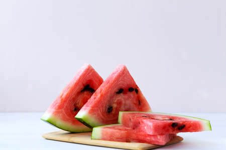 slices of watermelon.ripe red watermelon on the white background. fresh watermelon on the wooden cutting board on the table with copy space.の写真素材