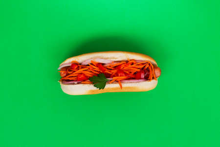 homemade hot dogs with carrot on the green table. tasty Hot dog with pickles, sauce and ketchup on a green background in a restaurant. Fast food concept with copy spaceの写真素材